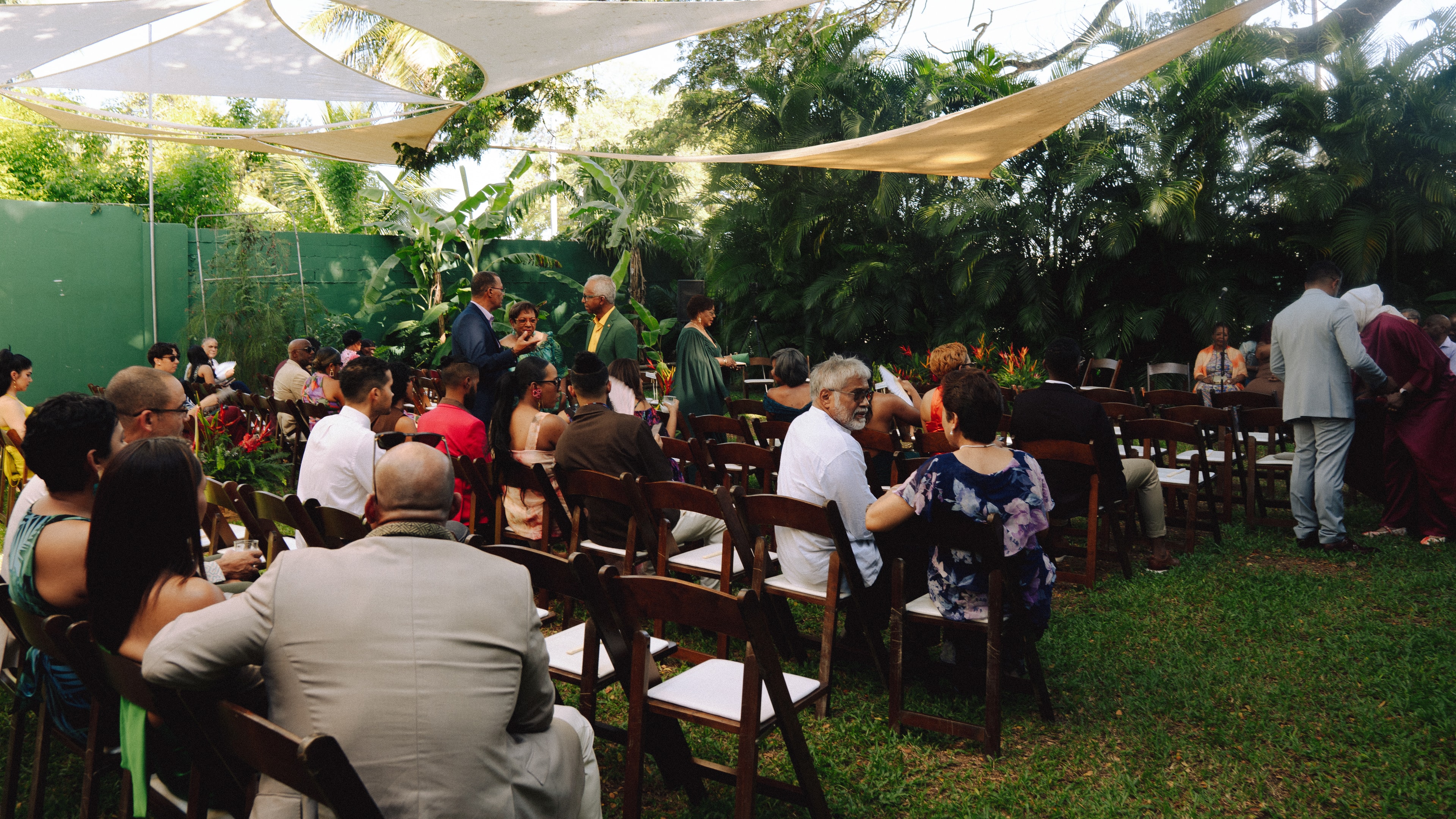 Wedding guests seated beneath shade sails before the outdoor ceremony