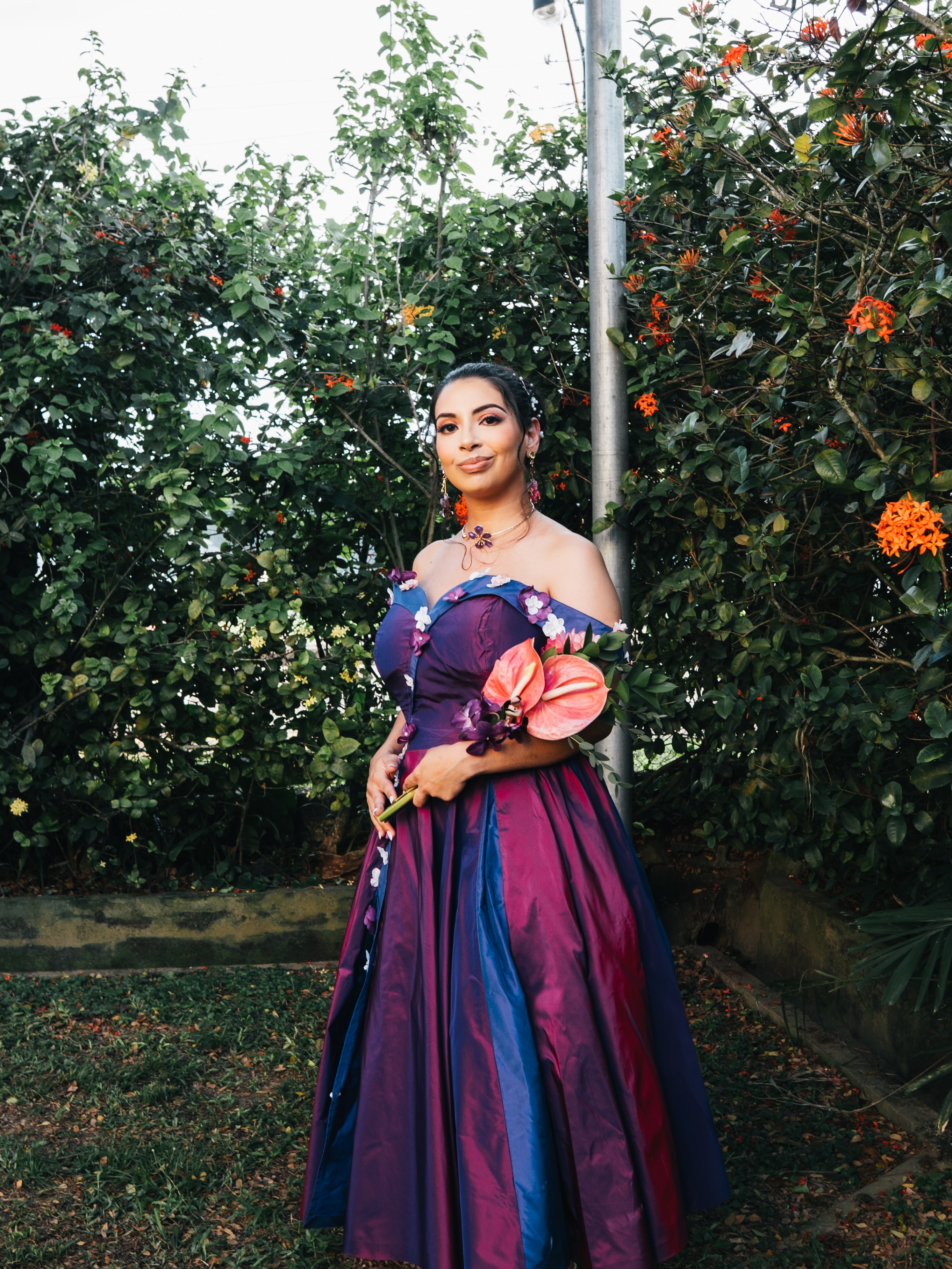 A bridesmaid in a purple dress holding a tropical bouquet